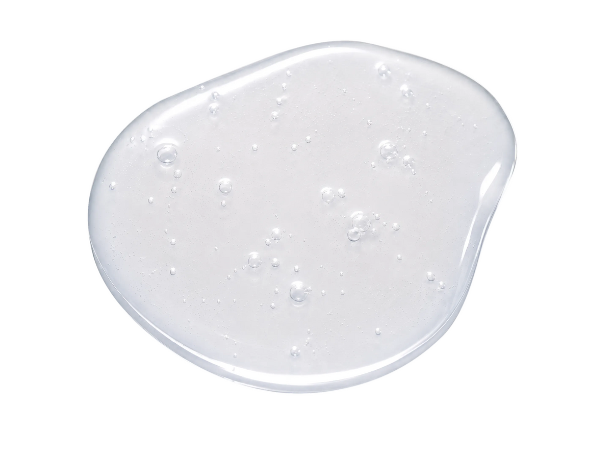 A glossy, translucent clear gel or serum droplet with small embedded air bubbles, presented on a solid white background.
