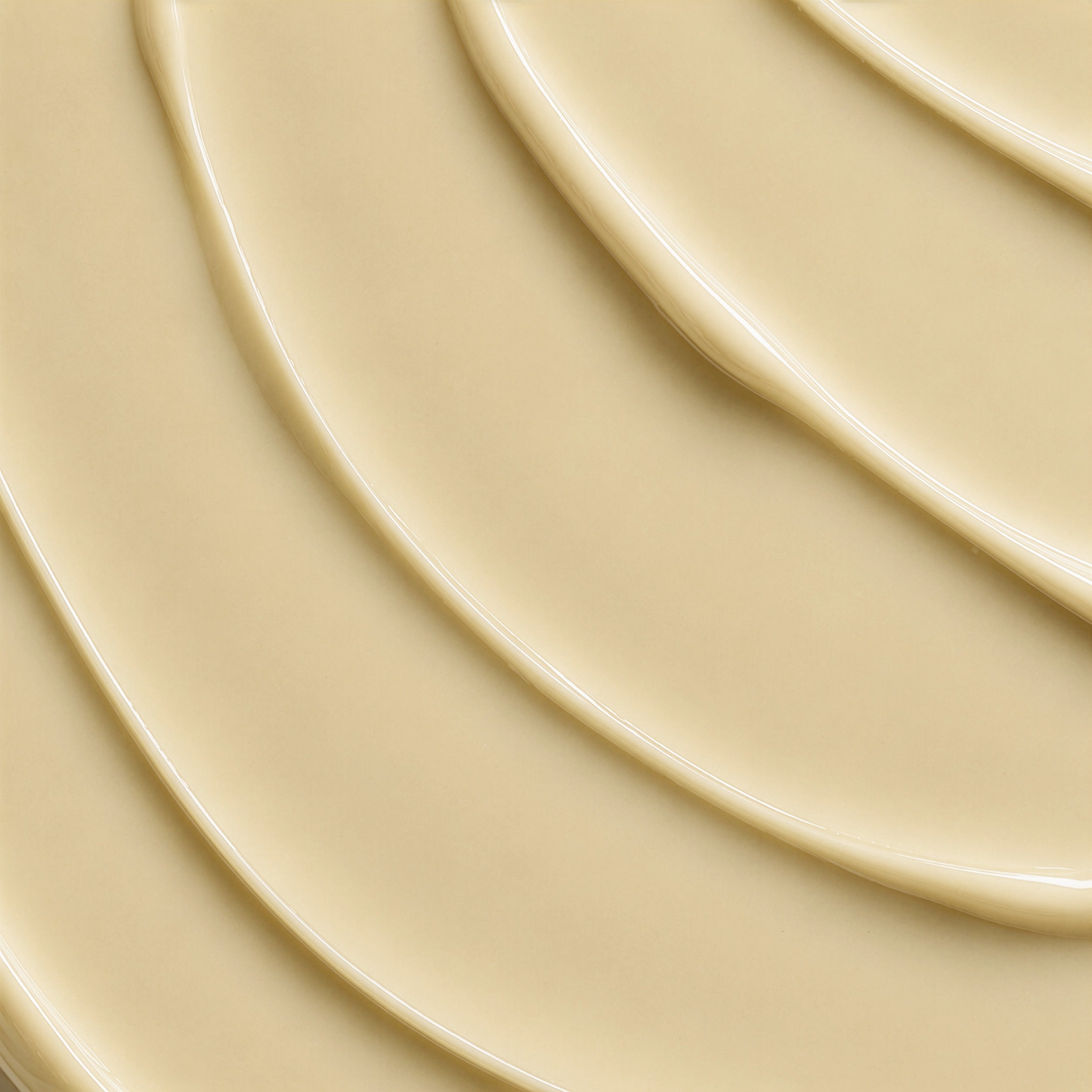 A close-up texture shot of a smooth, creamy beige cosmetic cream with elegant, flowing ridges.