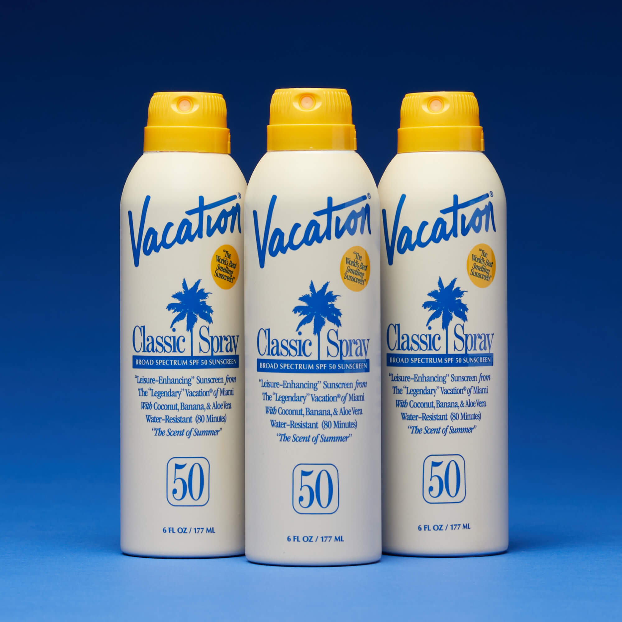 Three bottles of Vacation Classic Spray sunscreen on a blue background