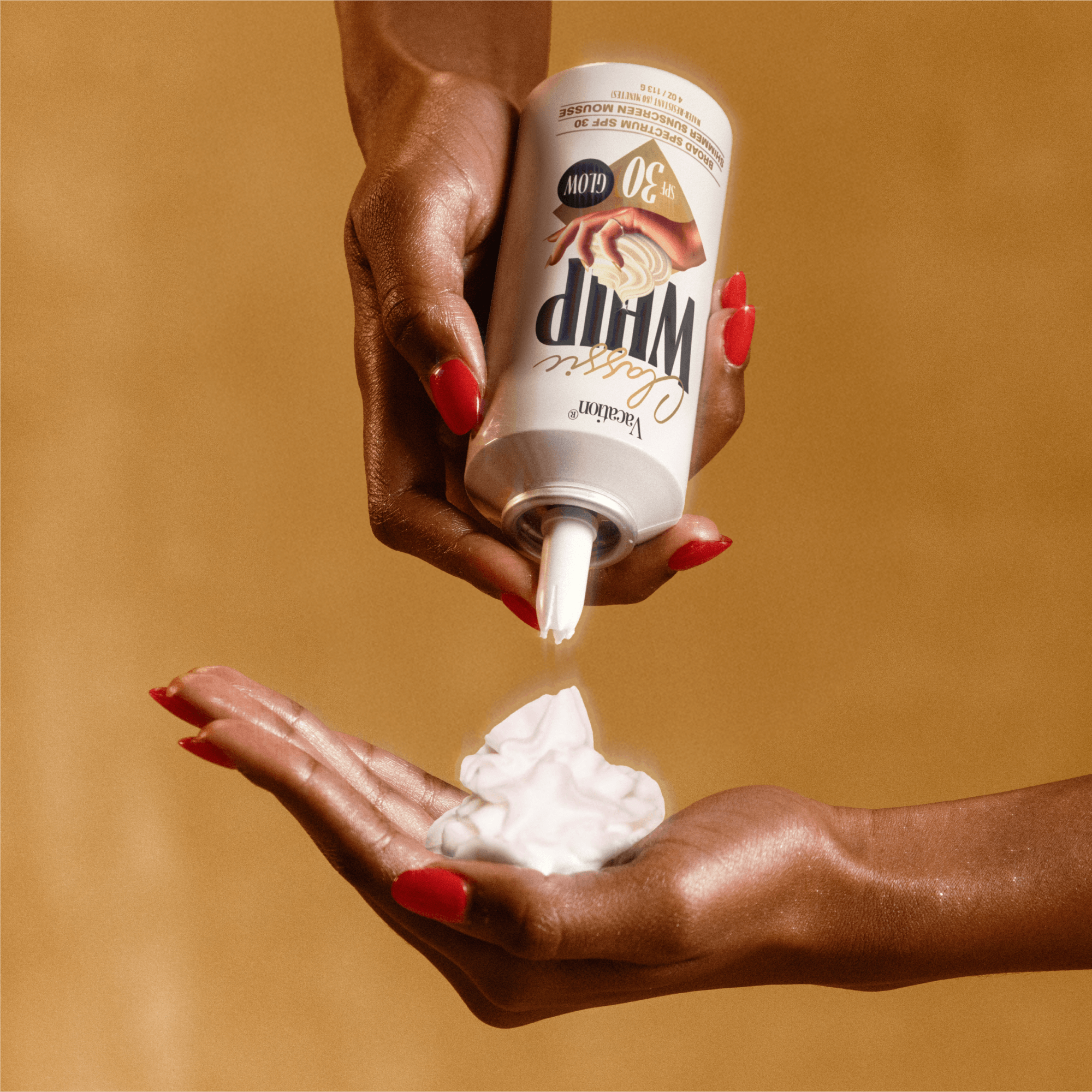 Hand holding a container of Sunscreen mousse bottle labeled 'Classic Whip' in front of a brown background