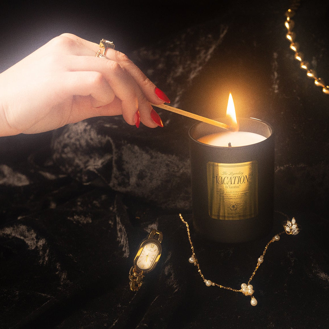Hand lighting a candle amongst gold jewelry