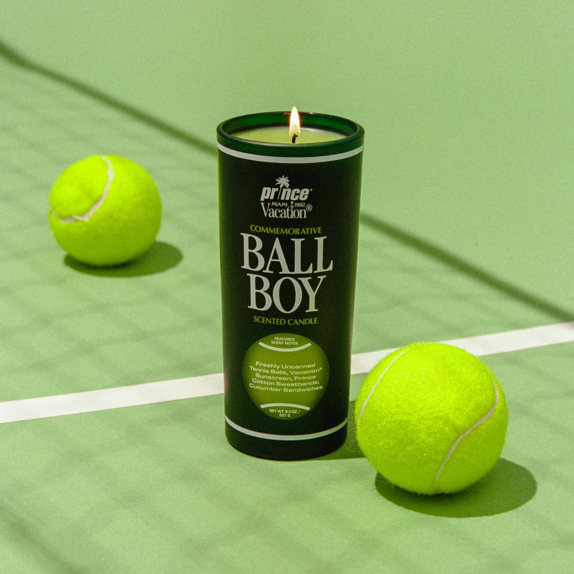 Candle labeled 'Ball Boy' on a green surface with tennis balls.