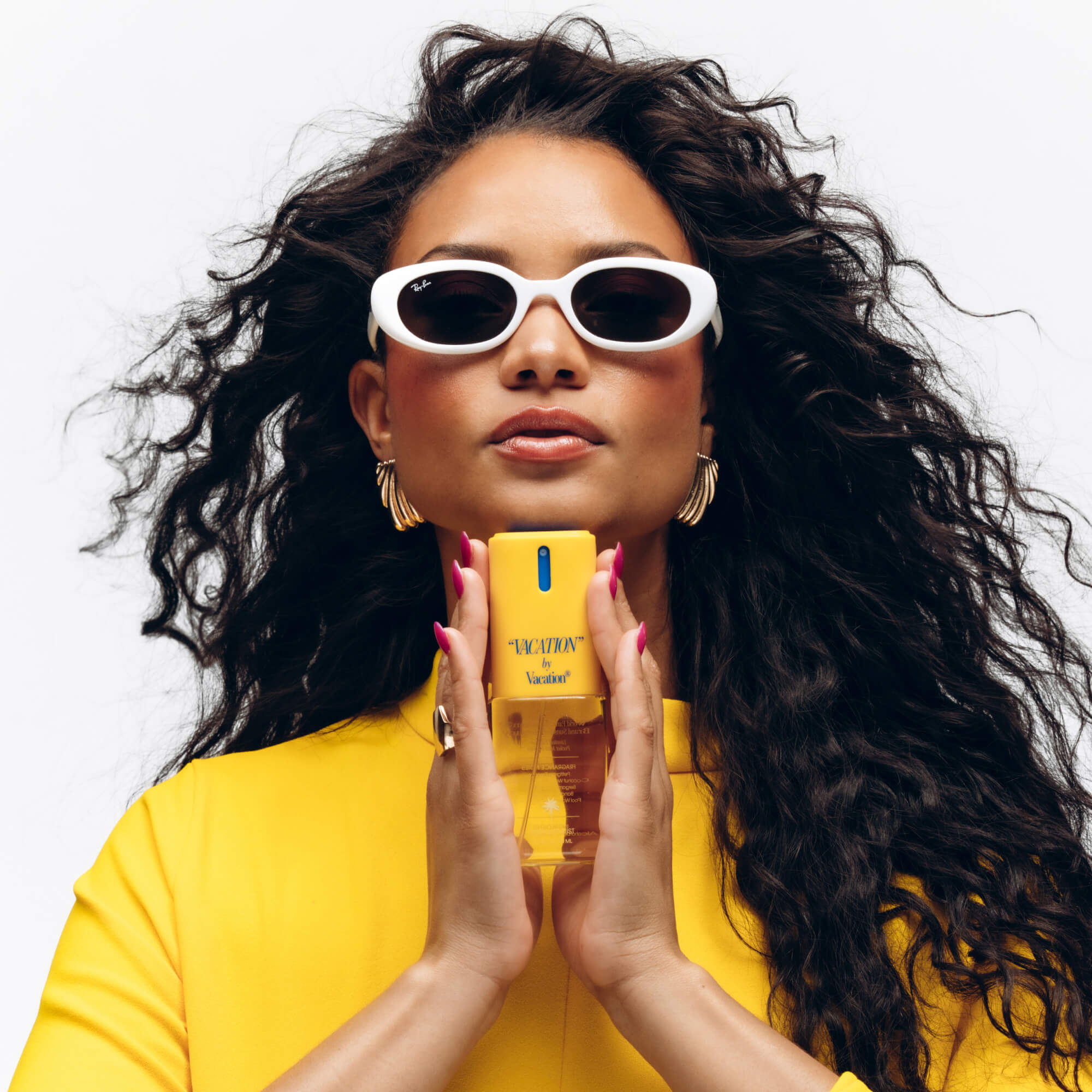 Woman holding a Vacation fragrance against a white background