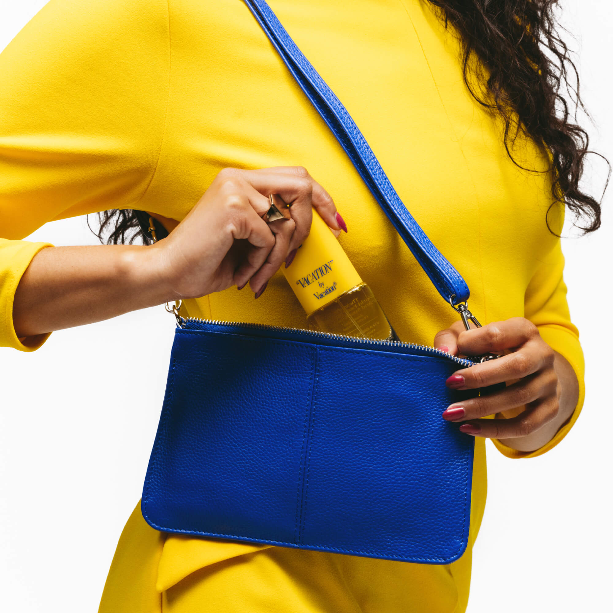 Person wearing a yellow outfit with a blue handbag, holding a yellow product.