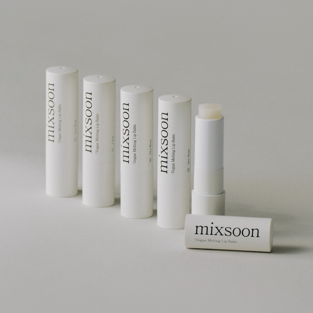 Five white cylindrical tubes of Mixsoon Vegan Moisturizing Lip Balm arranged on a light gray surface, with one tube standing open showing the balm stick and another lying in front.
