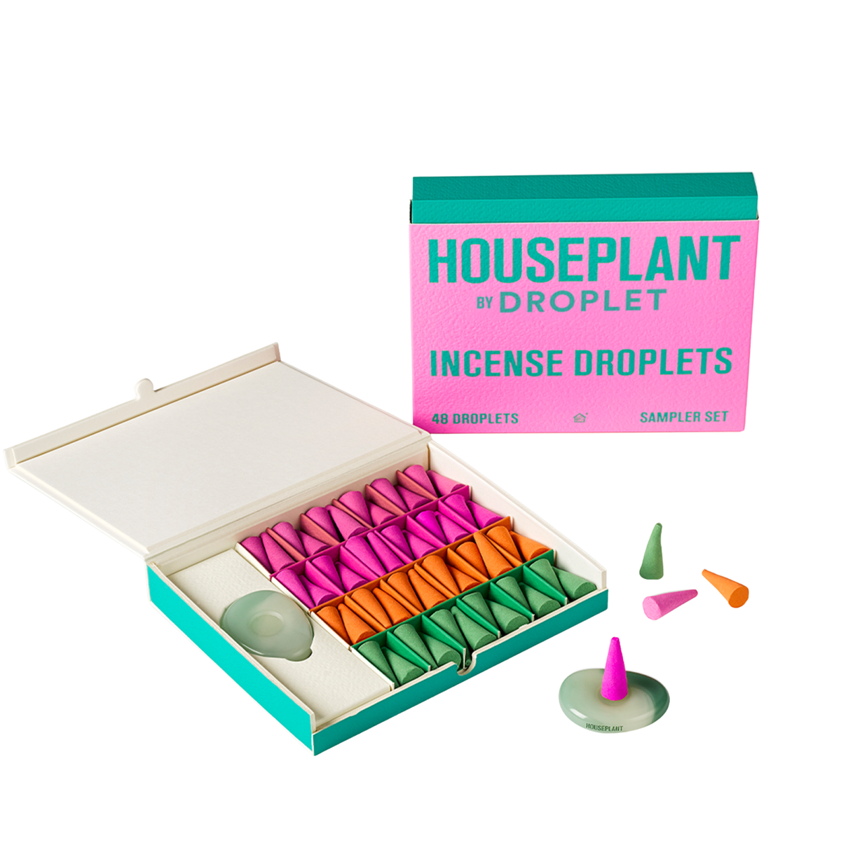 A boxed set of colorful incense droplets shown open, with the retail box standing behind it on a clean white background. The set includes multiple cone-shaped droplets in pink, orange, and green arranged in a tray, a few loose droplets, and a pale green incense stick holder.
