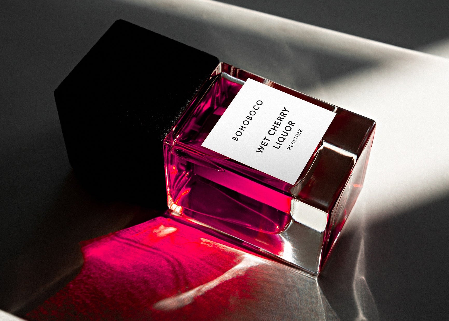 Pink glass bottle with a label on a reflective surface