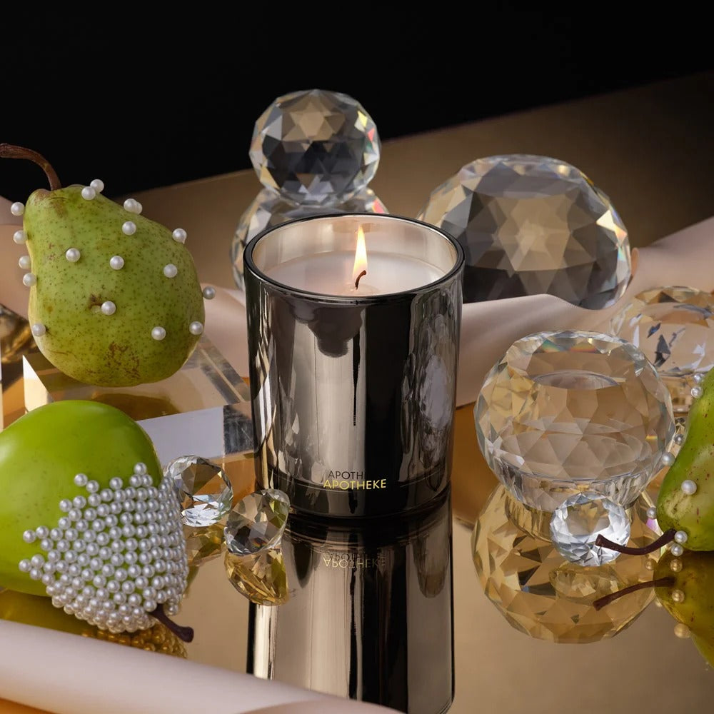 Black candle with a lit wick on a reflective surface with decorative elements