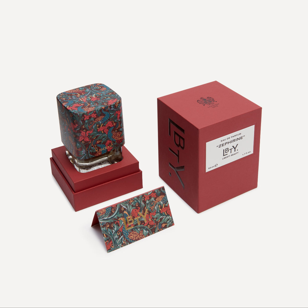 Liberty perfume bottle with floral design on a red stand and box, featuring the brand 'LBTY'.