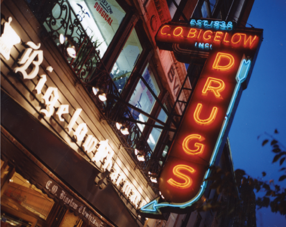 Neon signage outside the Bigelow store reading "Drugs"