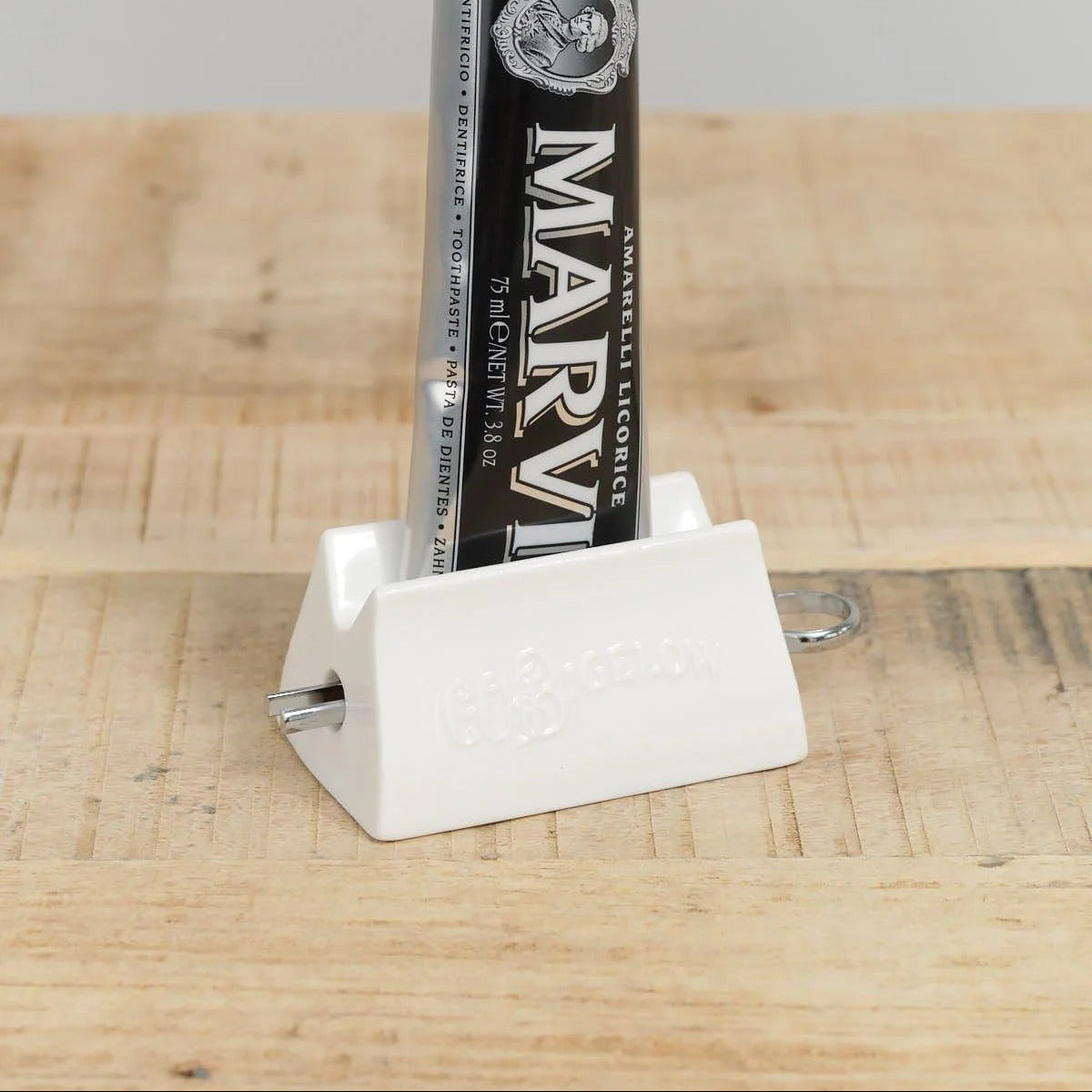 Marvis Toothpast Tube in C.O. Bigelow Ceramic Toothpaste Dispenser on a wood surface.