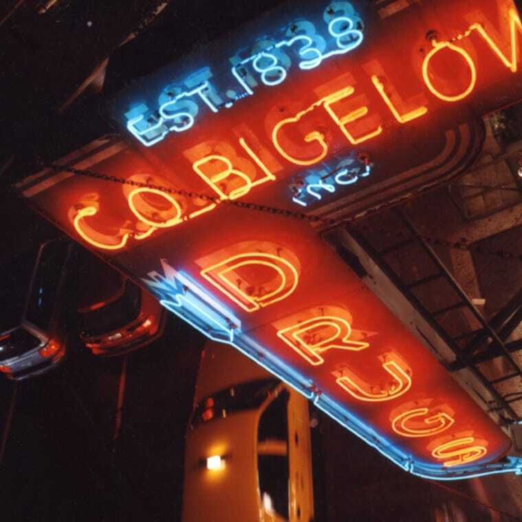 Neon lighting above the store reading "C.O. Bigelow Drugs, est. 1838"