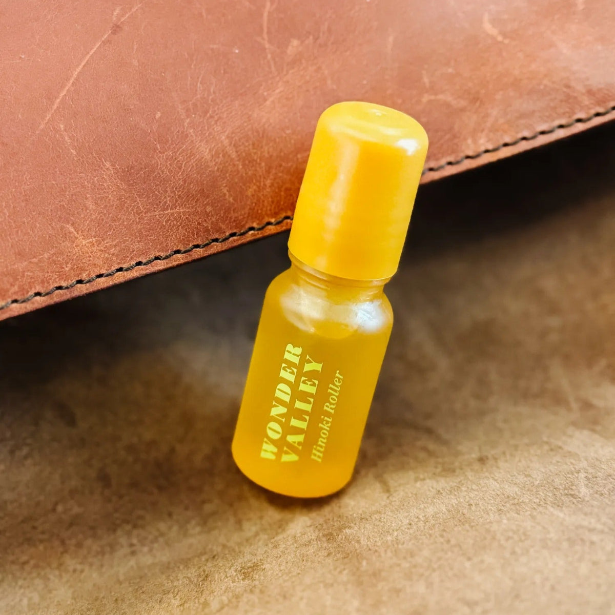 Small bottle with yellow cap and label on a brown leather surface