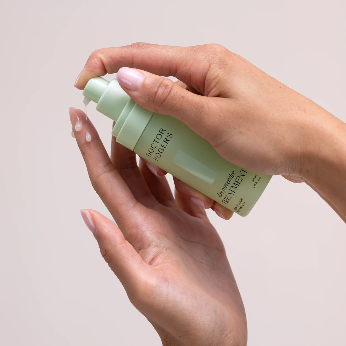 Hand holding a green skincare bottle with a neutral background