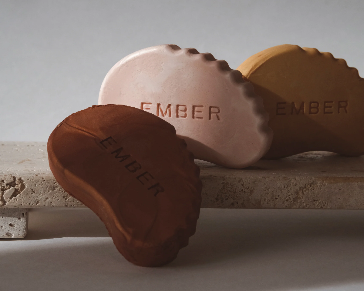 Three Ember Wellness Glow Bars in different colors on a stone surface with a neutral background.