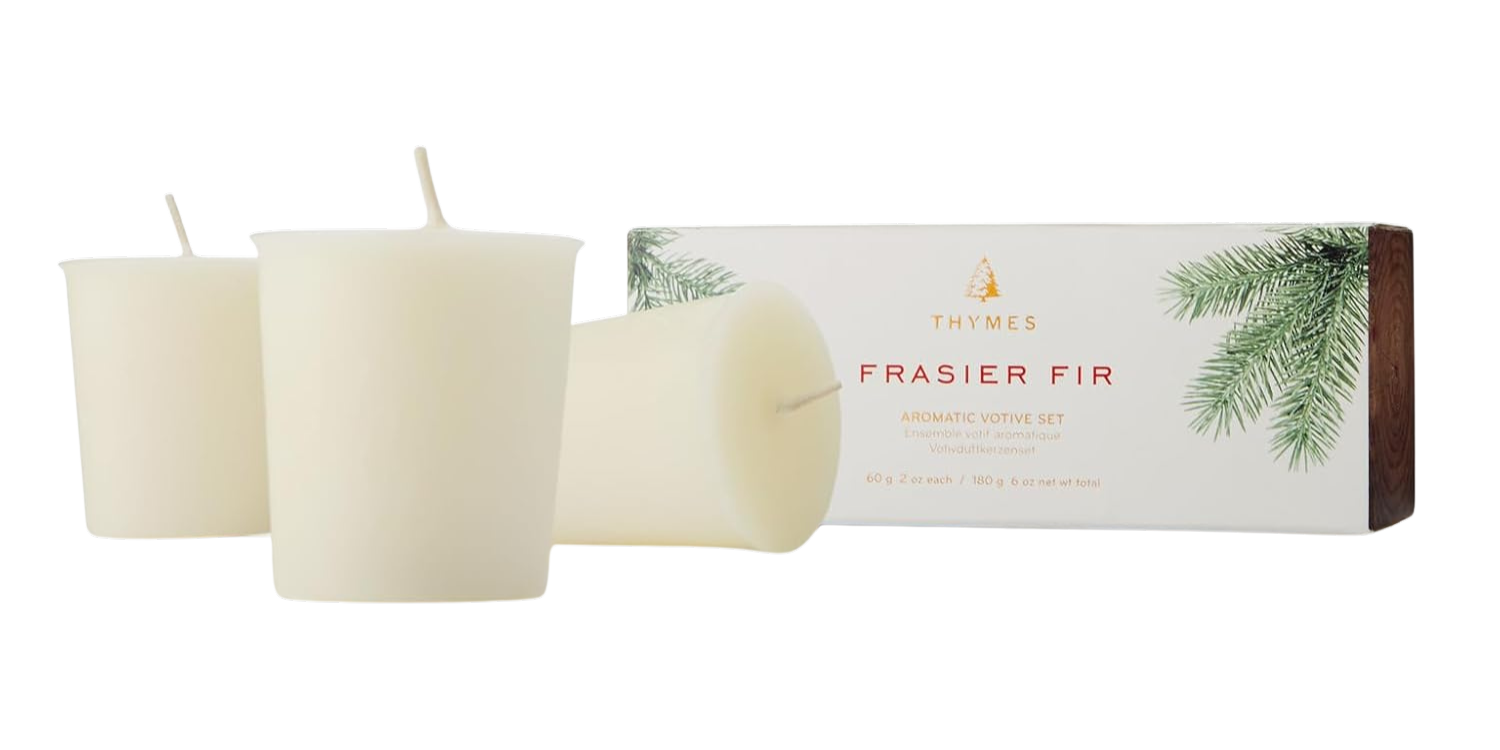Three white candles in front of their packaging labeled 'Fraser Fir' on a white background.