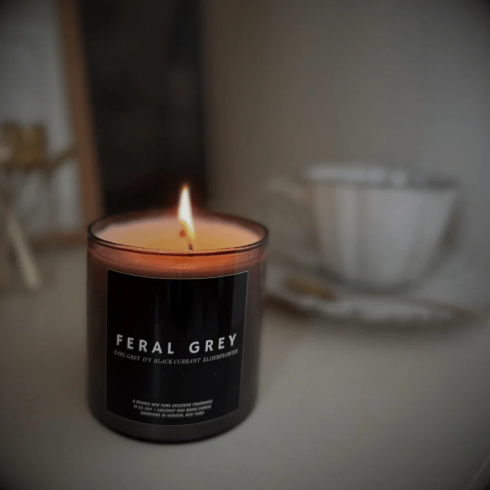 Candle labeled 'Feral Grey' with a blurred background