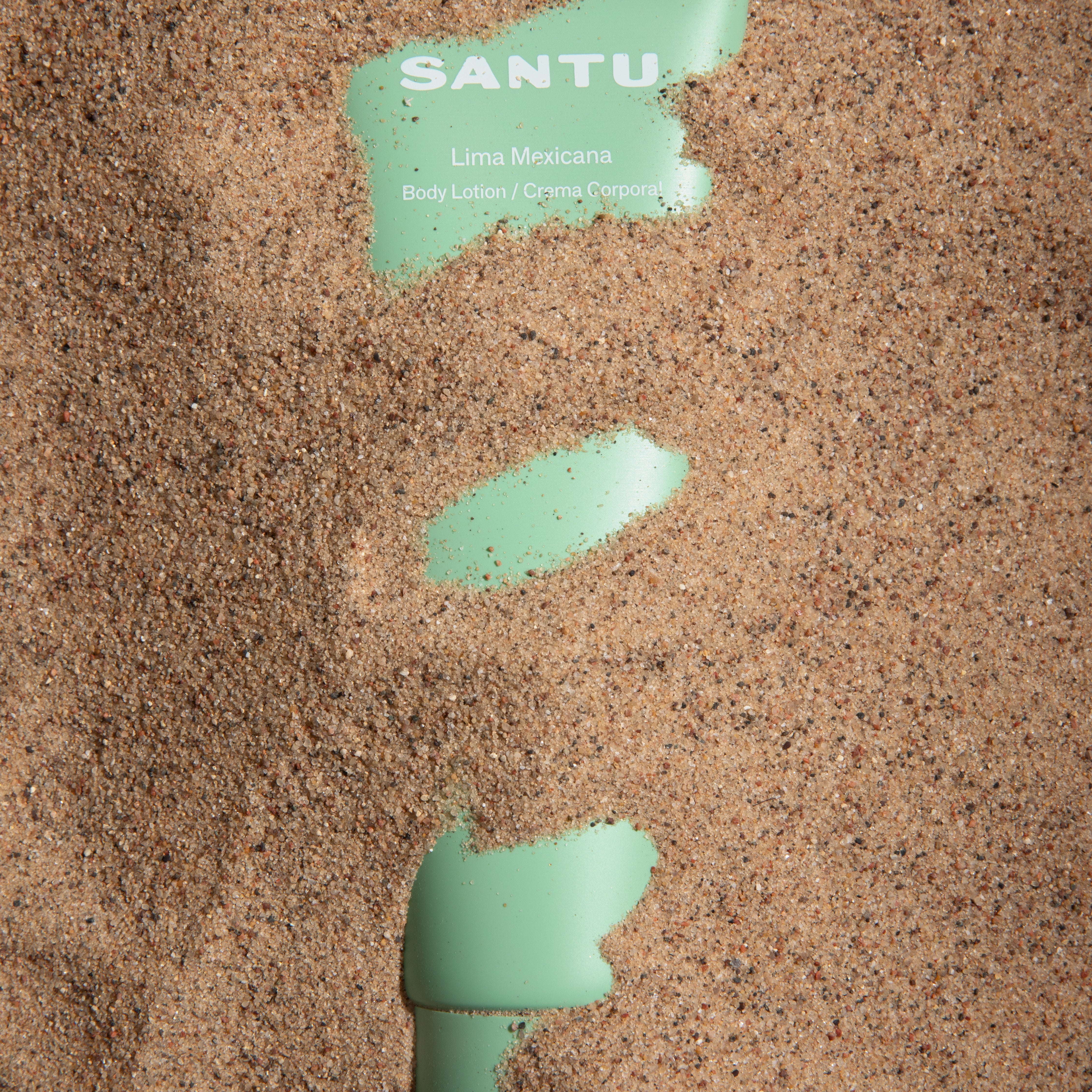Green body lotion smear on sand with 'SANTU' branding.