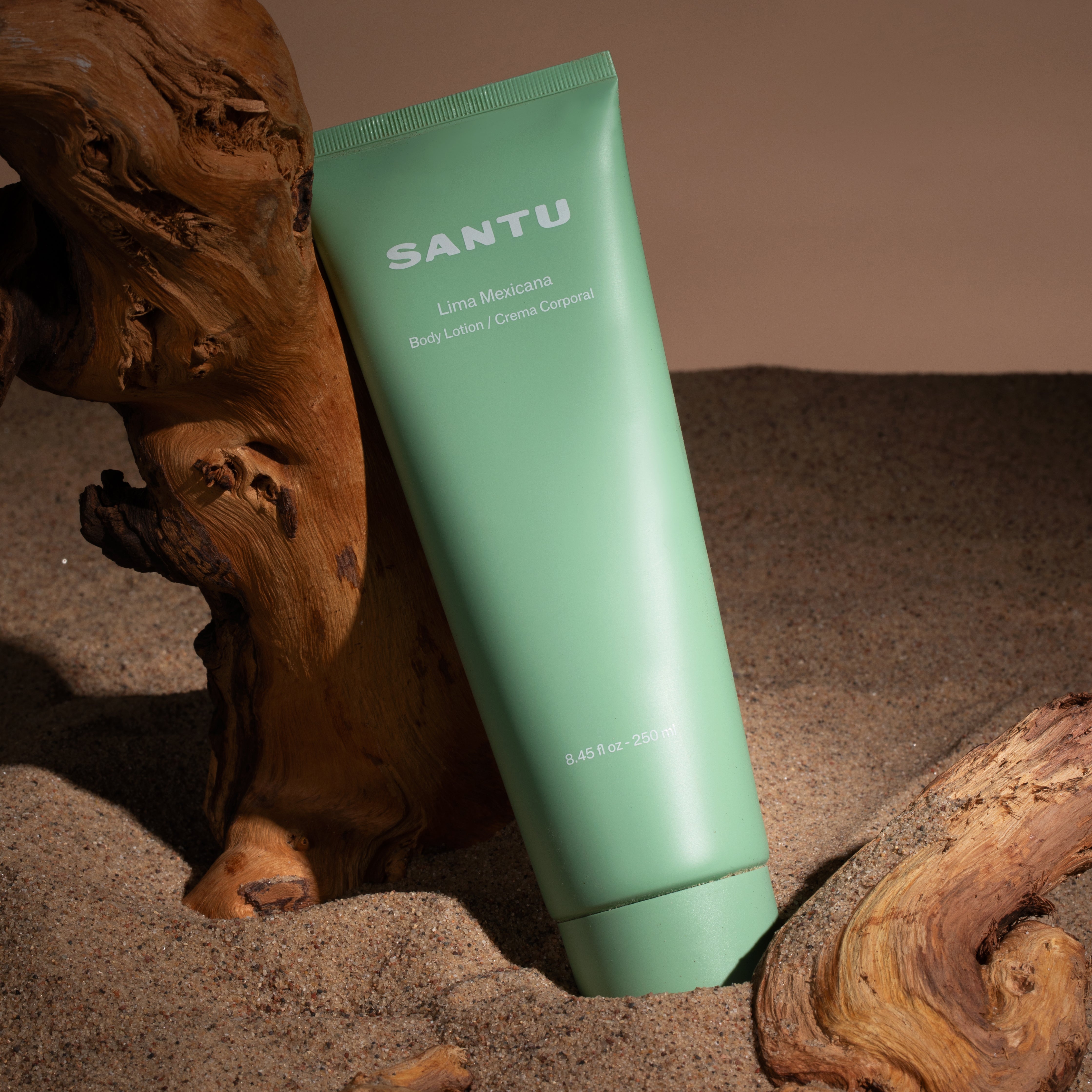 Green tube of Santu Lime Mexicana Body Lotion on a textured surface with wooden elements.