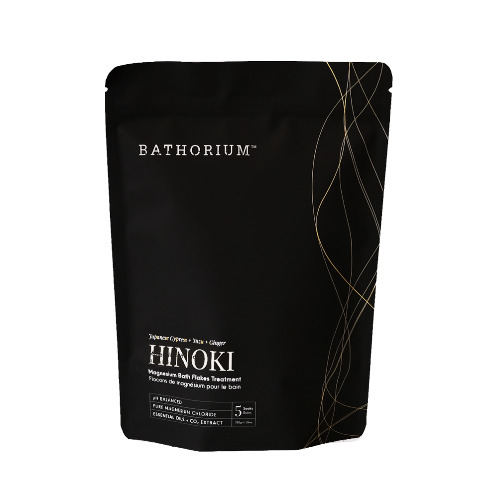 A black stand-up pouch of BATHORIUM HINOKI magnesium bath soak treatment, featuring white and gold text and line details on a plain white background.