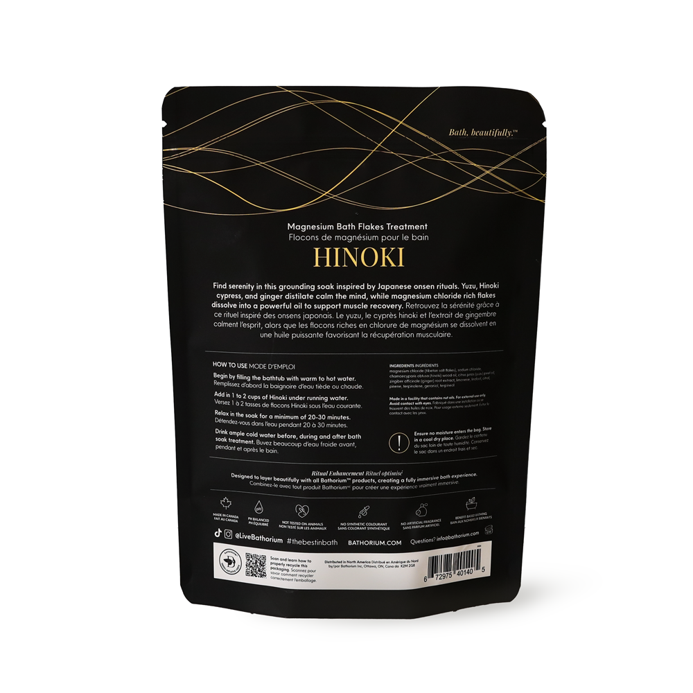 A black stand-up pouch of HINOKI Magnesium Bath Flakes Treatment with gold line accents and white text, photographed on a clean white background.