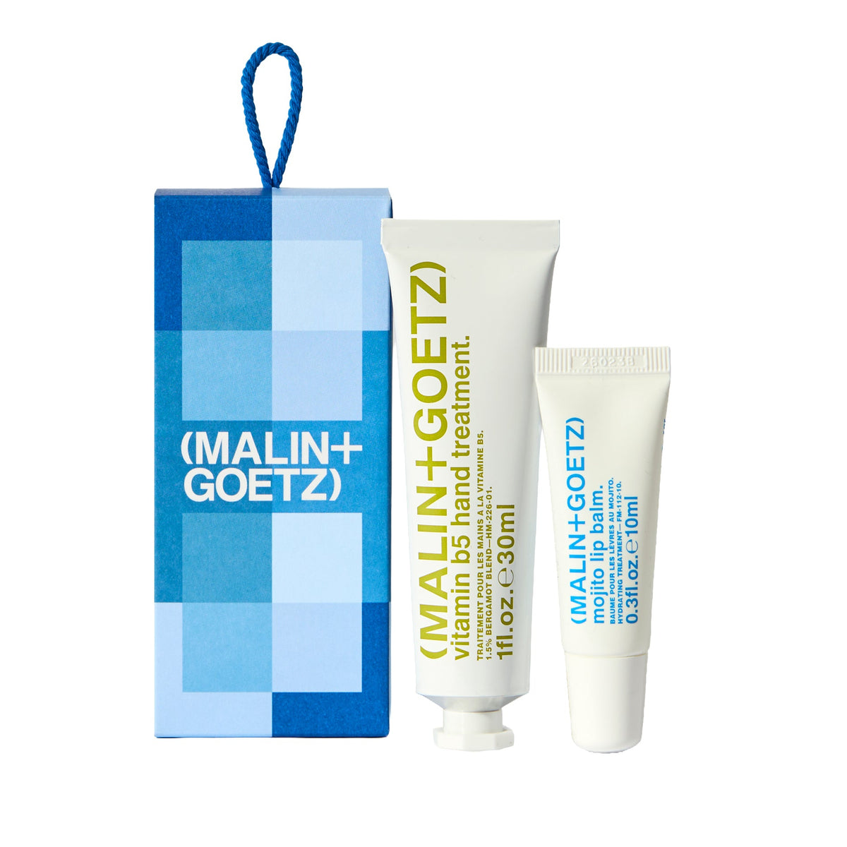 Malin+Goetz Vitamin B5 Hand Treatment gift set featuring a blue and white geometric box with a blue hanging loop, alongside two white squeeze tubes of hand treatment.