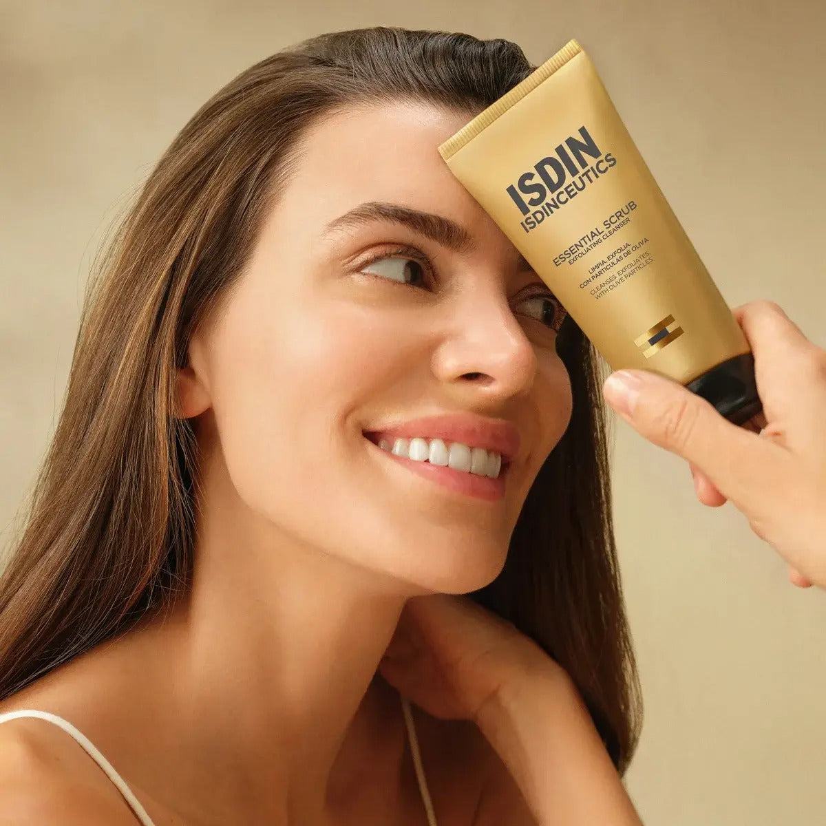Woman holding ISDIN ISDINCEUTICS Essential Scrub product against her forehead