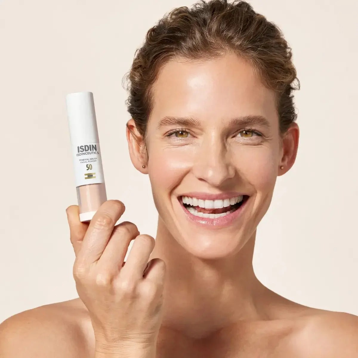 Woman holding a skincare product with a beige background
