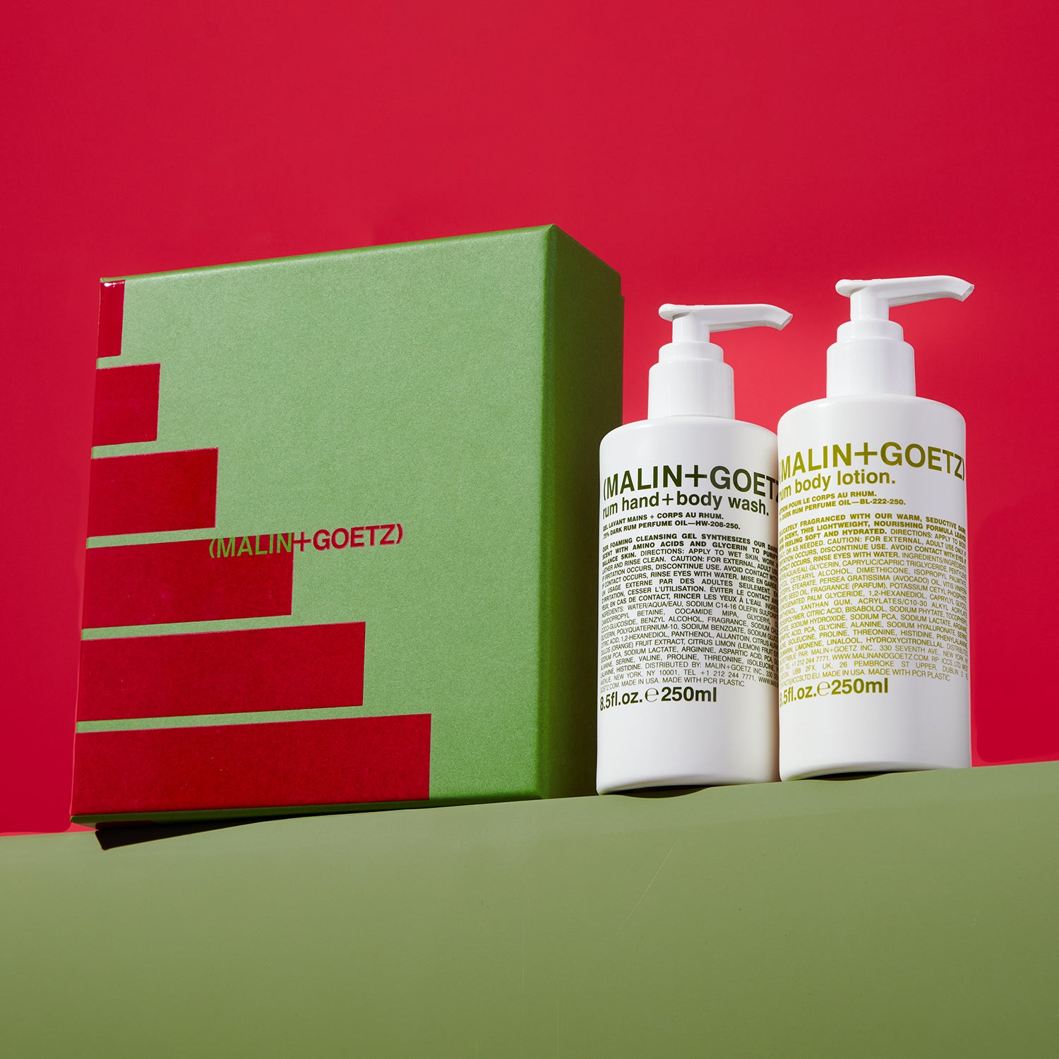 A bottle of MALIN+GOETZ body lotion and body wash with a green box on a red and green gradient background.