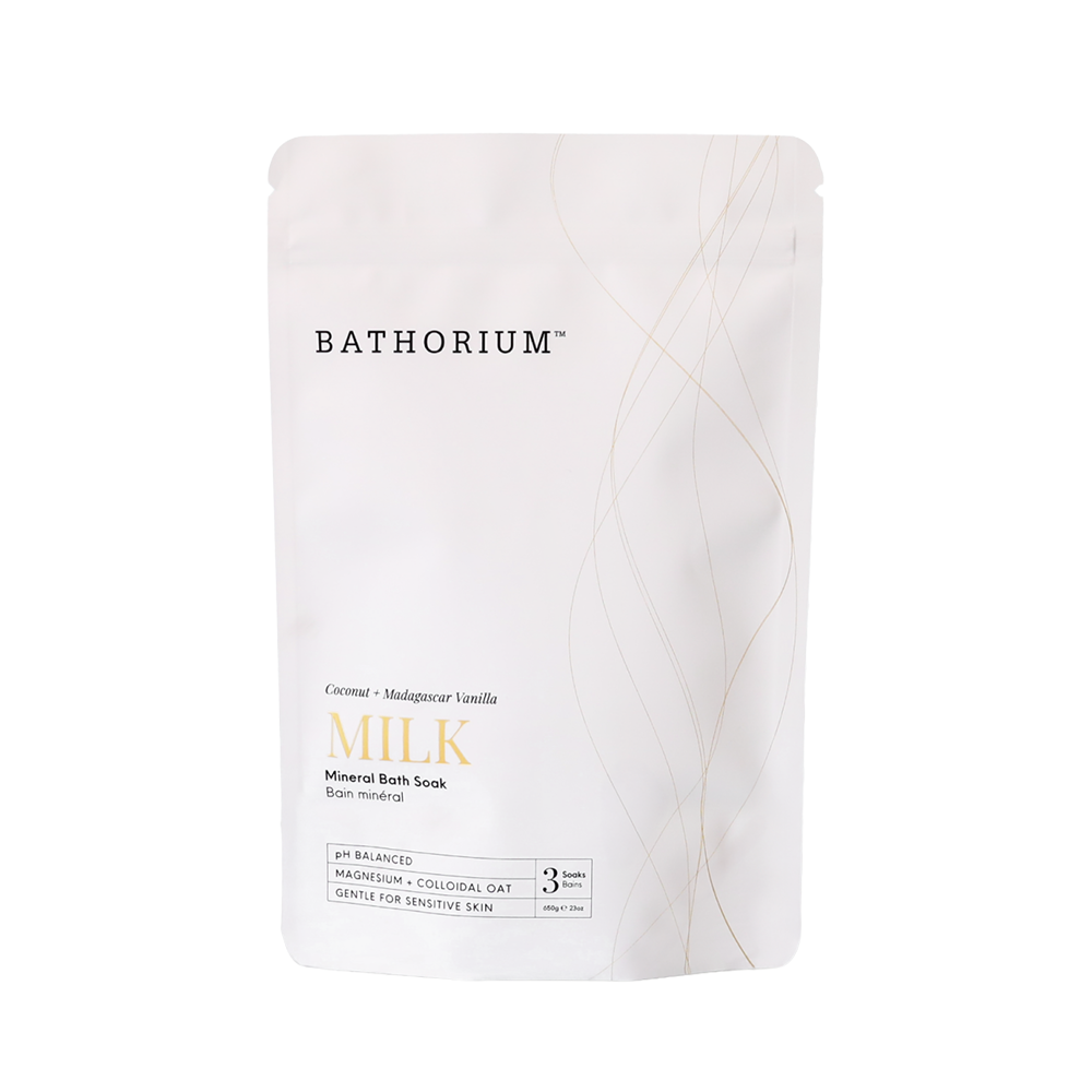 A white stand-up pouch of Bathorium Milk Mineral Bath Soak, featuring elegant gold wavy lines and gold lettering on a clean white background.