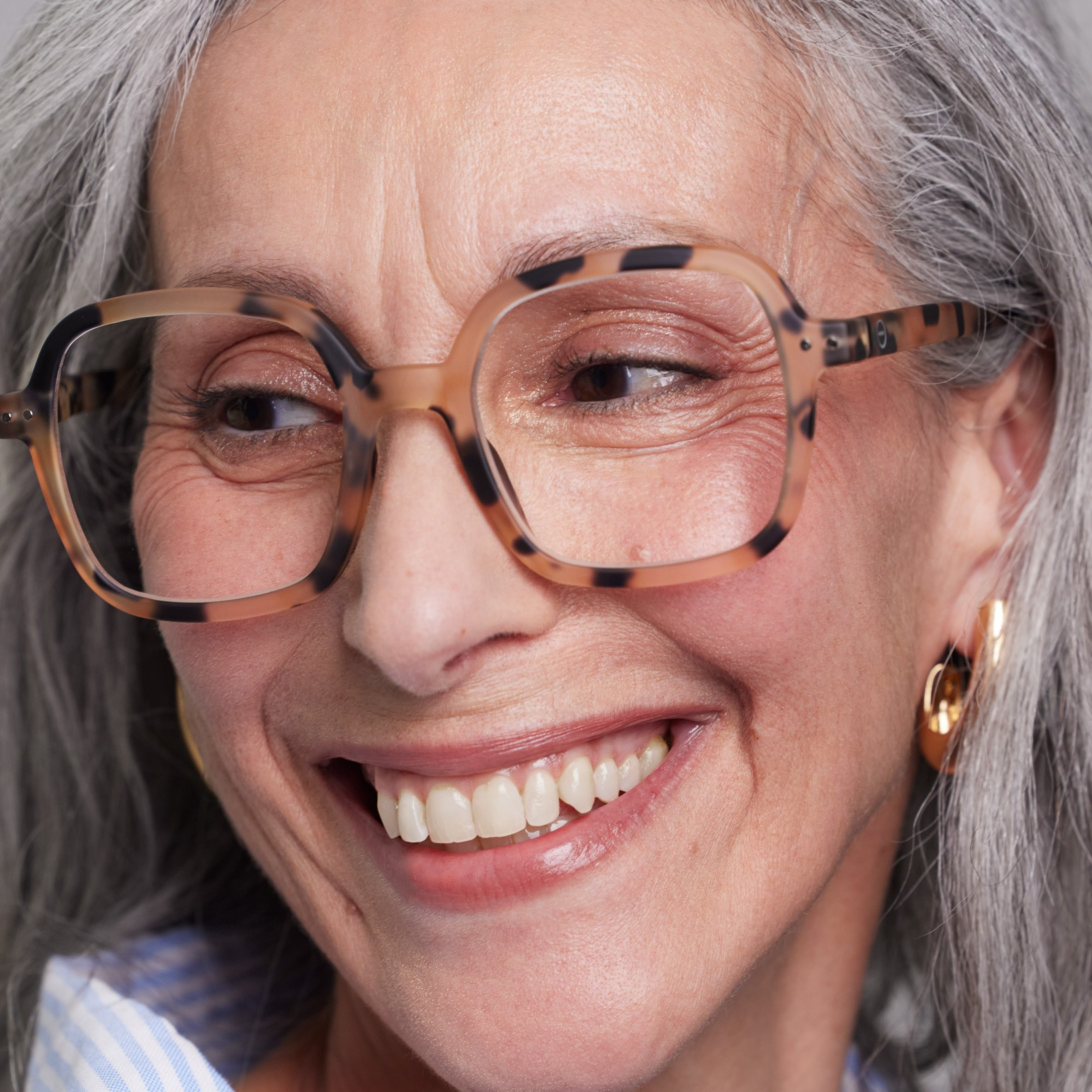 Close-up of a woman wearing glasses with a gray background