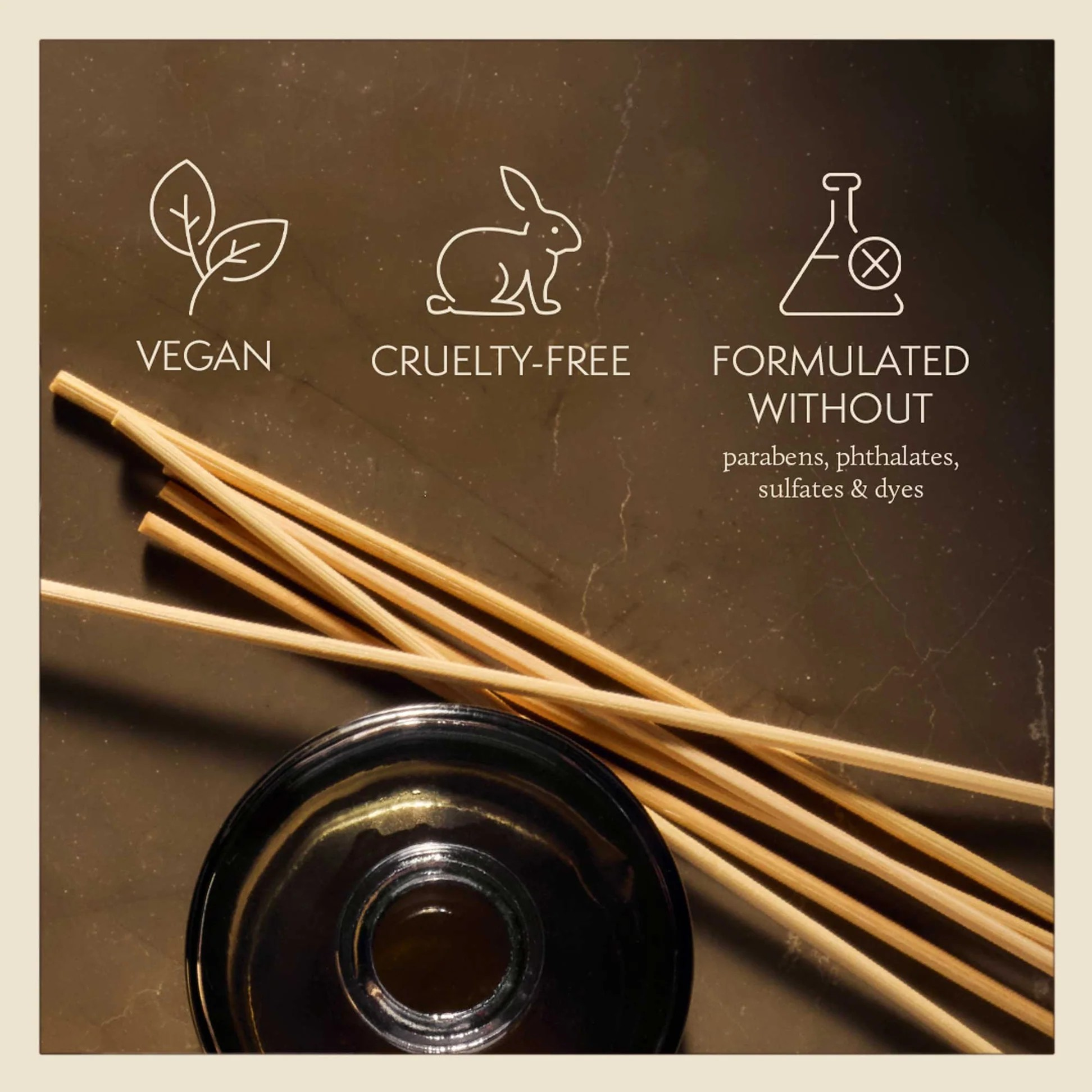 Vegan, cruelty-free, and sulfate-free product with reed diffuser and black container on a brown background.