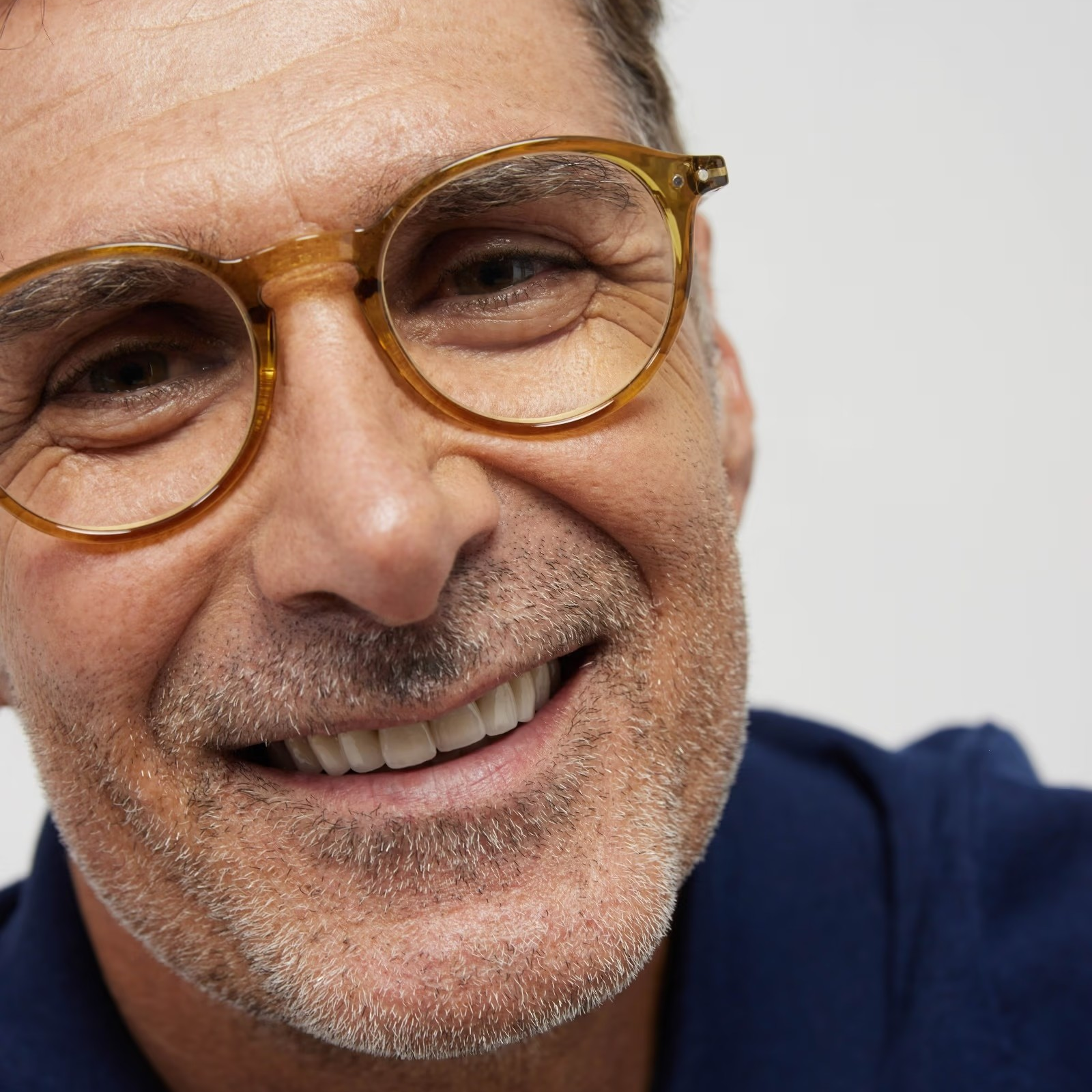 Man wearing glasses and a blue shirt against a white background