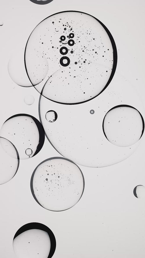 Video of clear fluid with bubbles slowly moving through on a white background