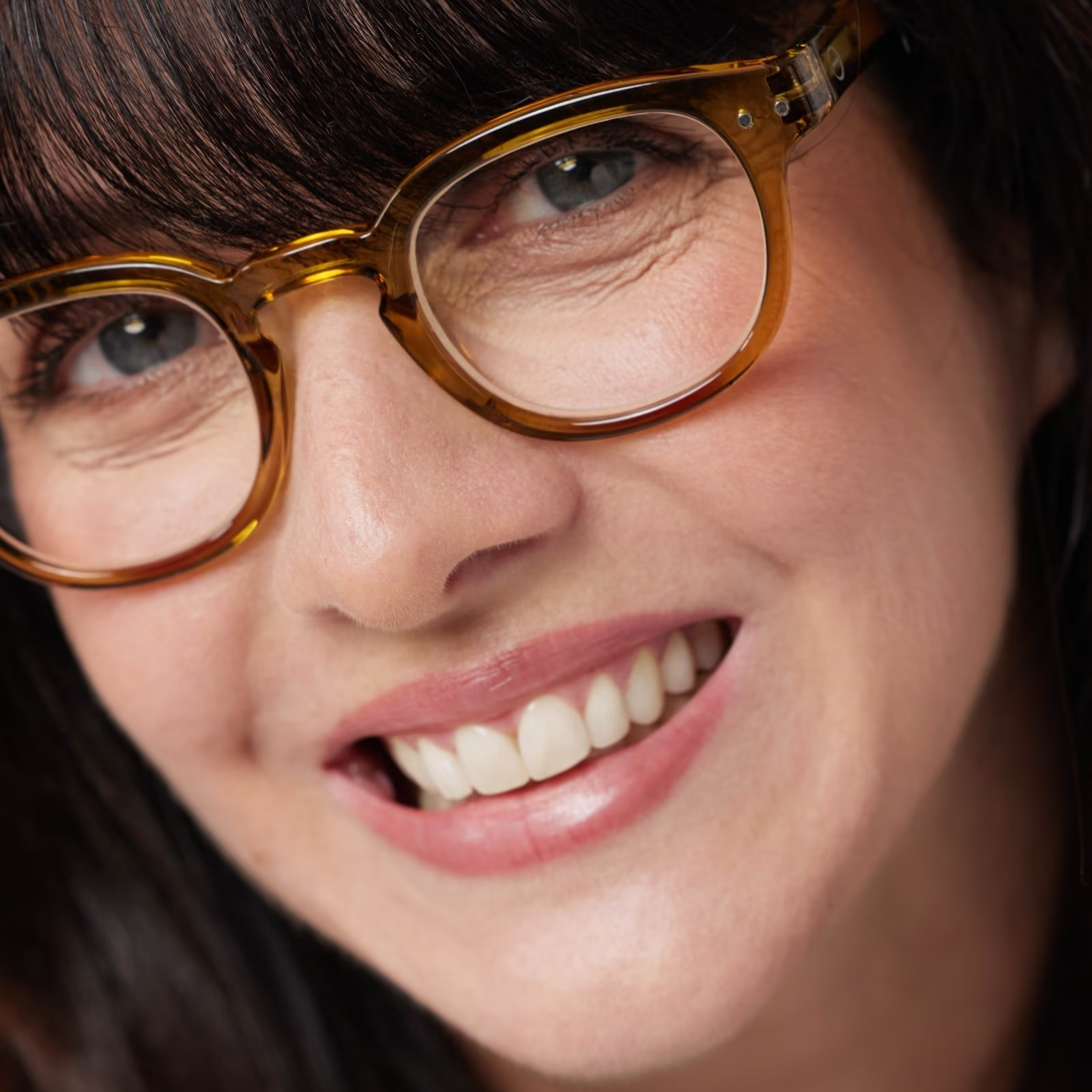 Close-up of a person wearing glasses with a neutral background