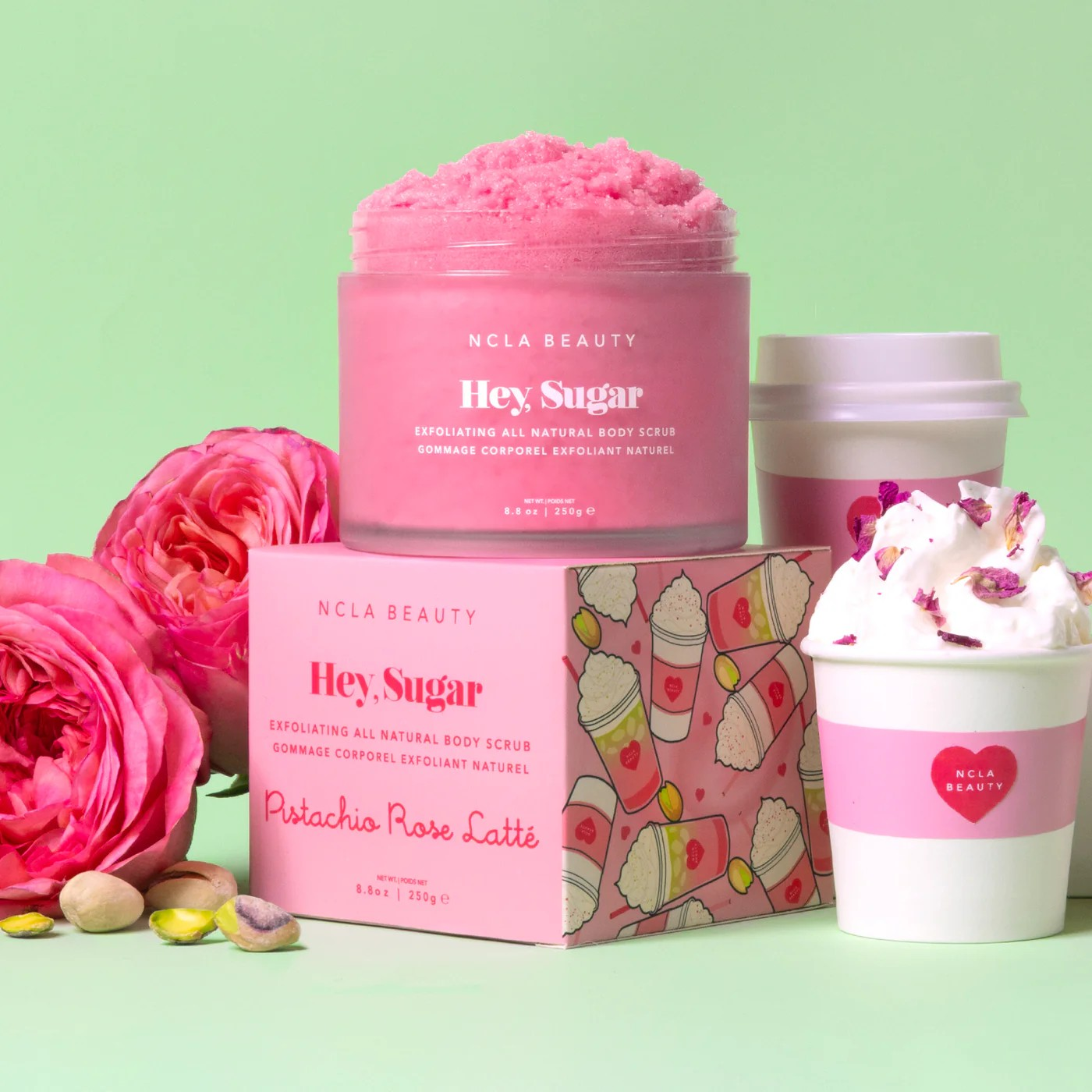 NCLA Beauty 'Hey Sugar' body scrub with packaging and pink roses on a light green background