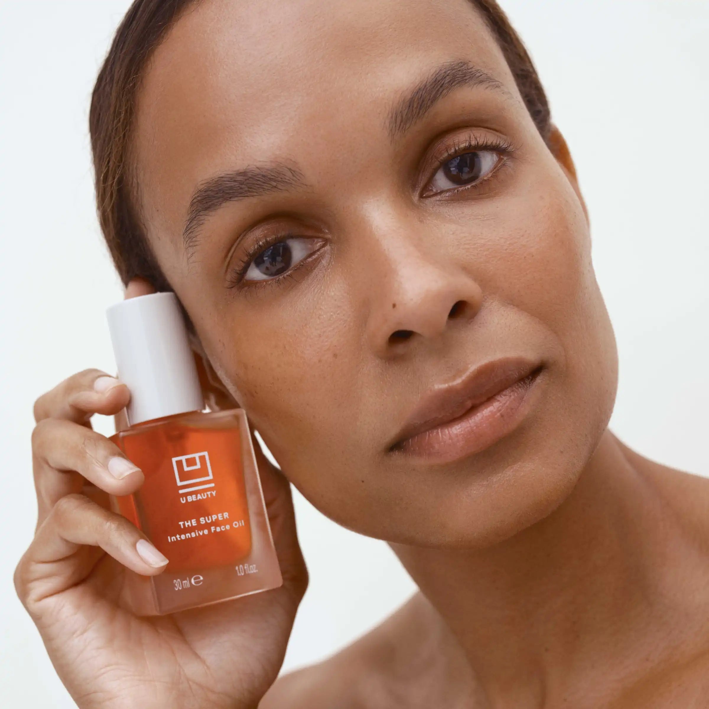 Woman holding a skincare product with a neutral background