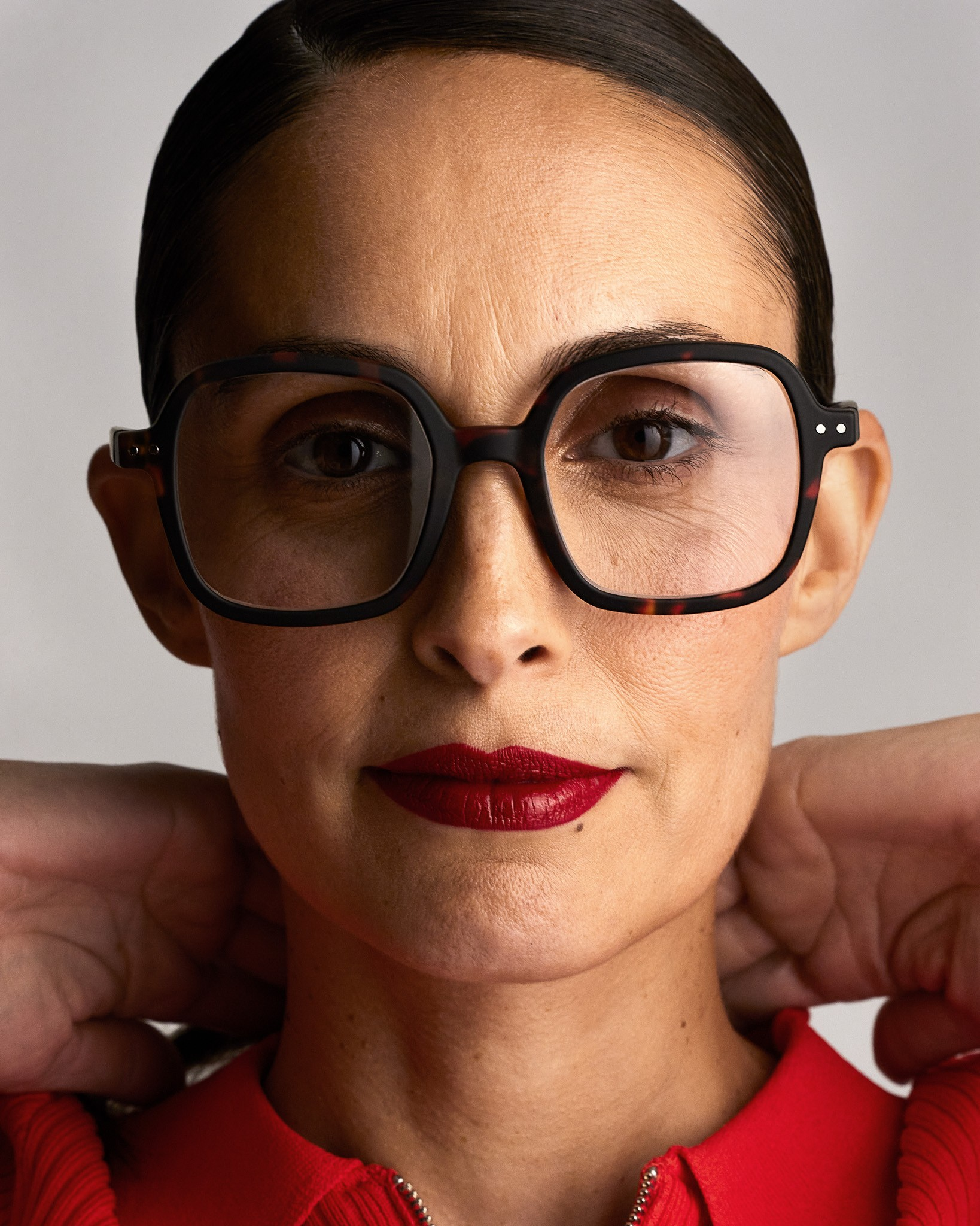 Woman wearing large black-framed glasses with a neutral background