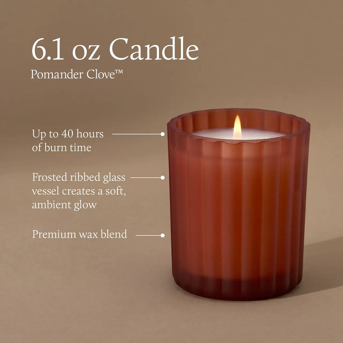 A lit 6.1 oz Pomander Clove candle in a frosted ribbed glass vessel, shown on a warm taupe background with descriptive text callouts about burn time, glass finish, and wax blend.