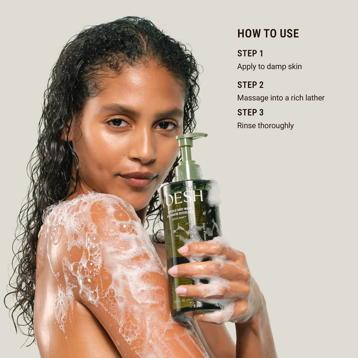 Woman with soap suds on her shoulders holding a bottle of VOESH soap, with usage instructions displayed.